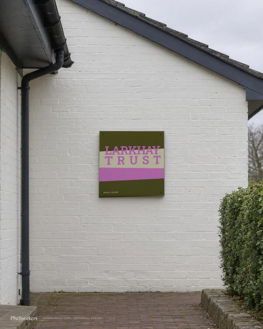 A torn-paper annual review cover mounted as a square panel beside a village hall entrance.